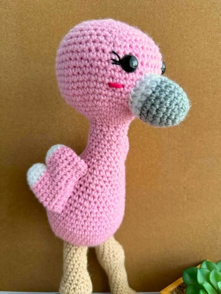 handmade crochet tall pink flamingo with rosy cheeks, long legs, and fluffy wings