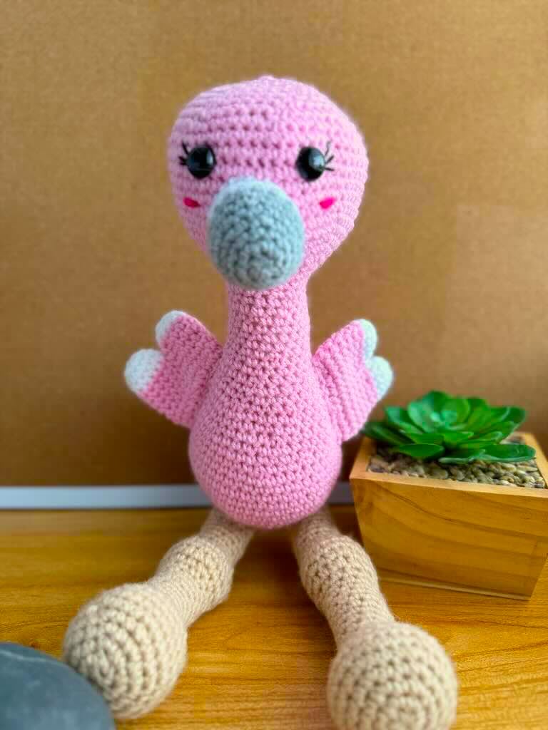 handmade crochet tall pink flamingo with rosy cheeks, long legs, and fluffy wings