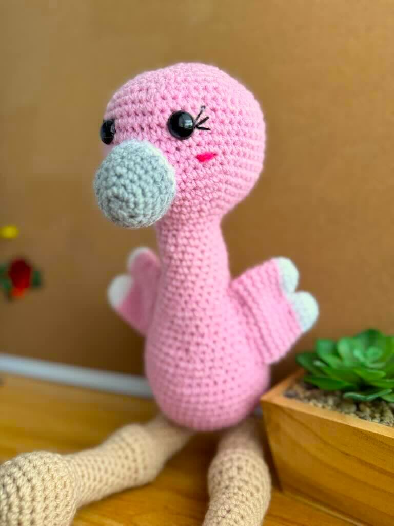 handmade crochet tall pink flamingo with rosy cheeks, long legs, and fluffy wings