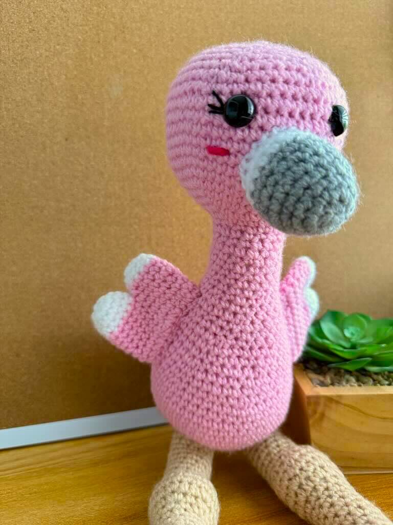 handmade crochet tall pink flamingo with rosy cheeks, long legs, and fluffy wings