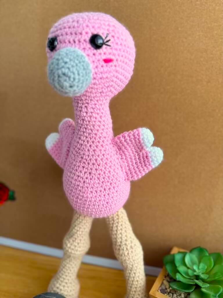 handmade crochet tall pink flamingo with rosy cheeks, long legs, and fluffy wings