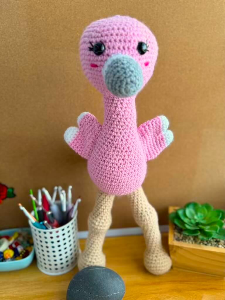 handmade crochet tall pink flamingo with rosy cheeks, long legs, and fluffy wings
