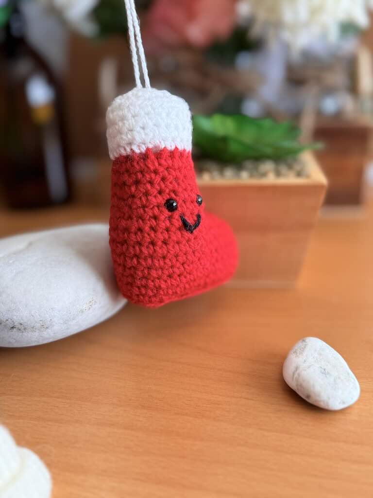 handmade crochet Christmas stocking in red and white with festive details