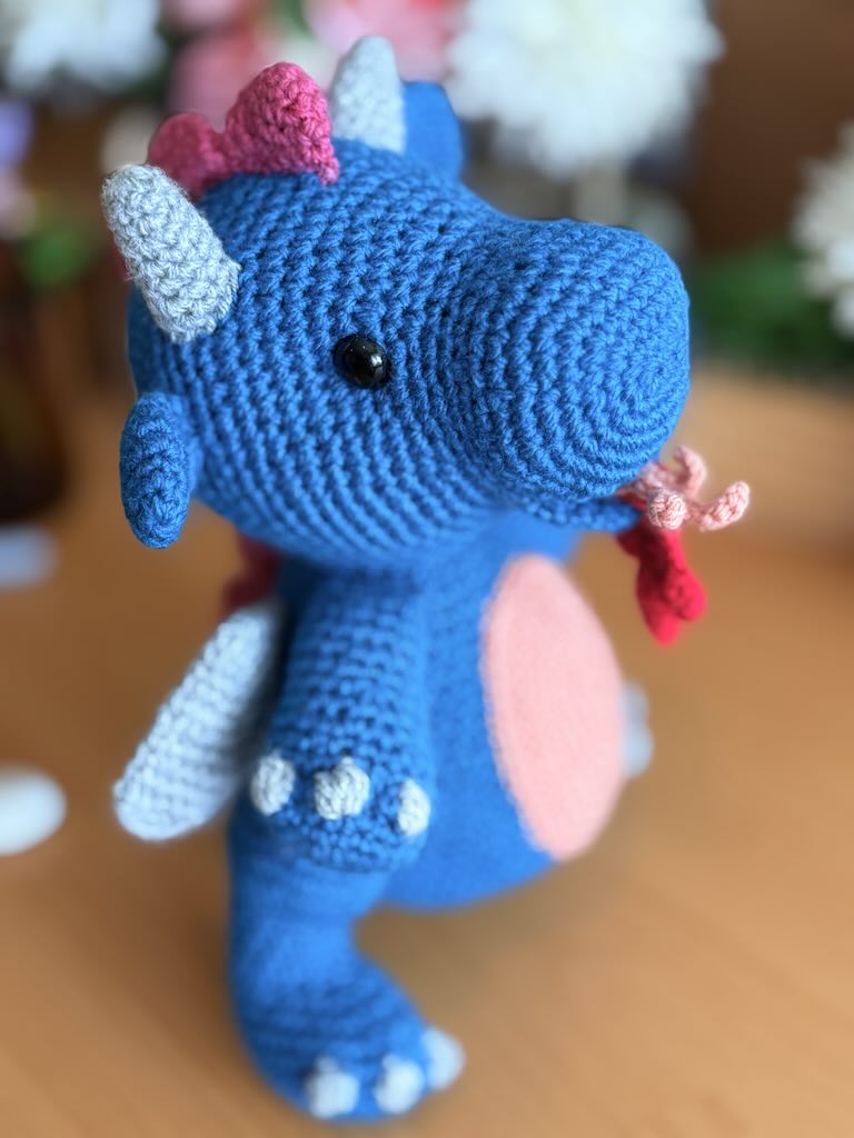 crochet fire-breathing dragon toy with pink tummy and cheerful expression