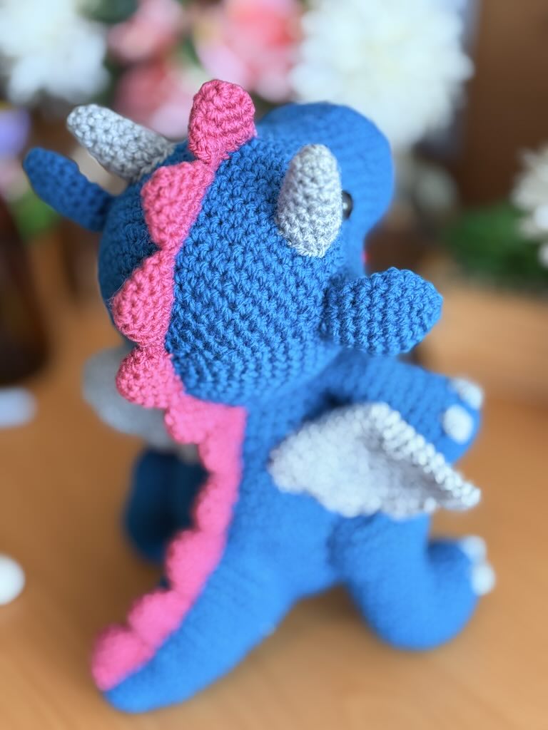 crochet fire-breathing dragon toy with pink tummy and cheerful expression