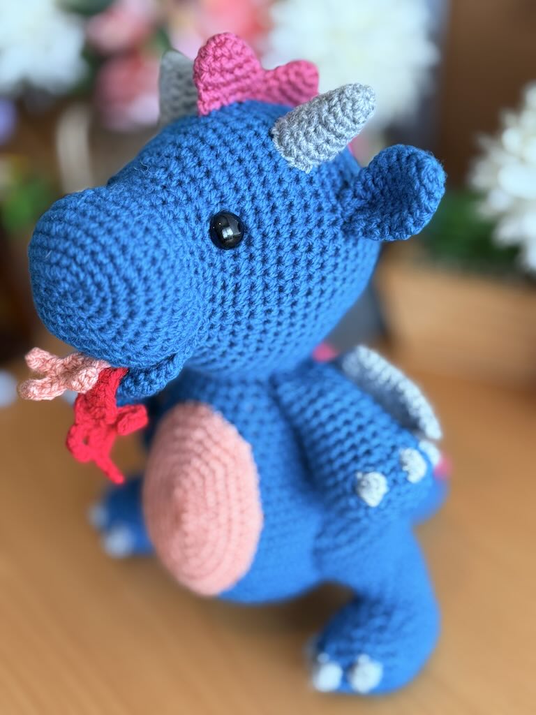 crochet fire-breathing dragon toy with pink tummy and cheerful expression