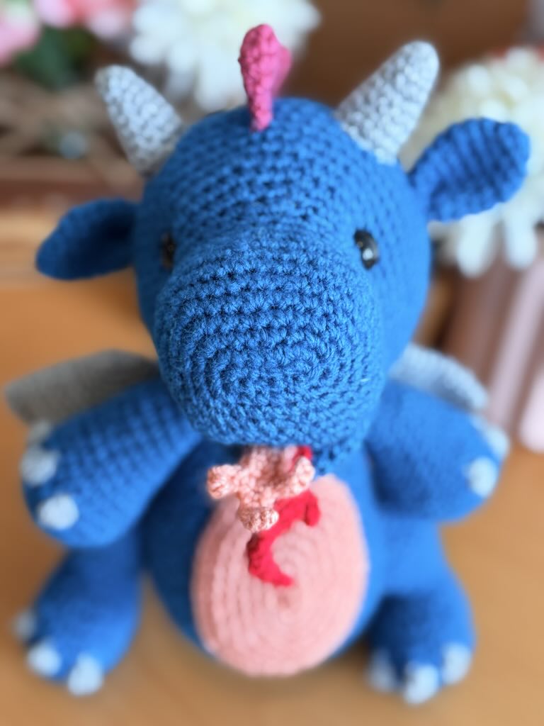 crochet fire-breathing dragon toy with pink tummy and cheerful expression