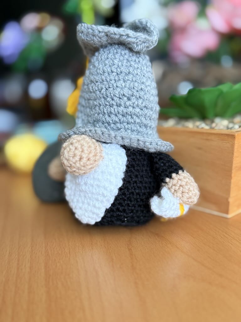 crochet gnome wearing graduation cap and gown, holding diploma