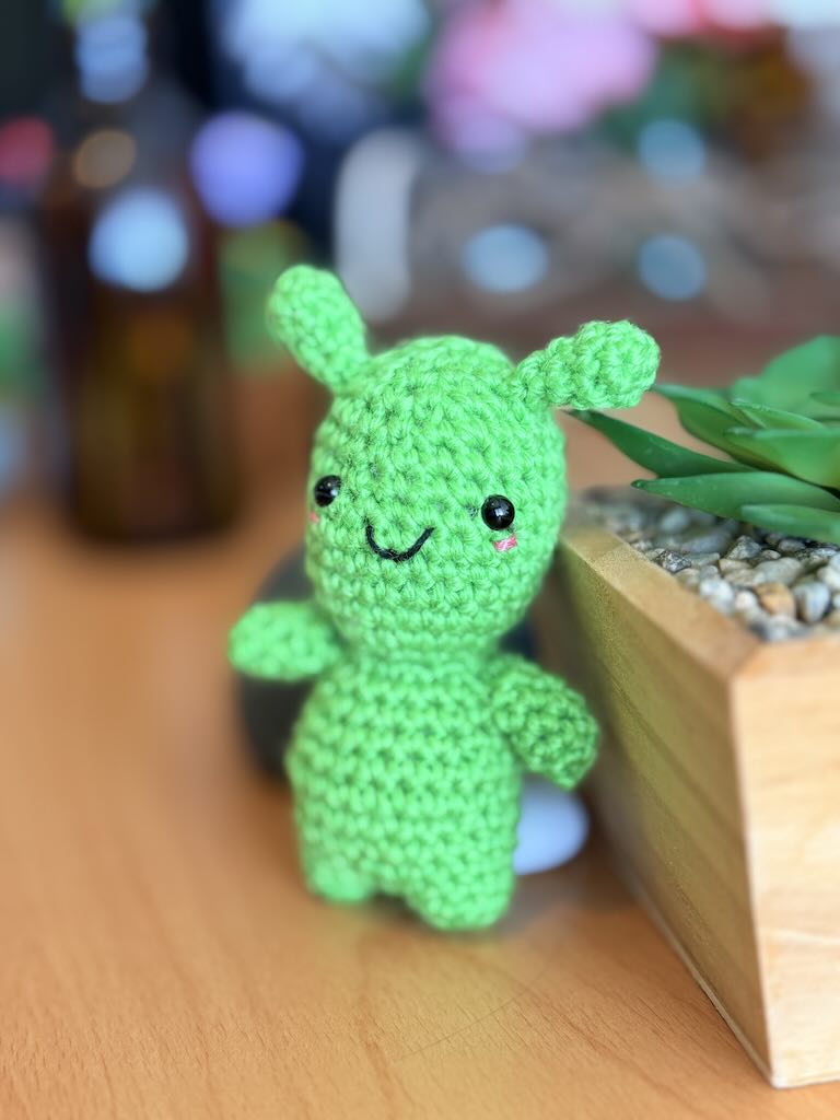handmade crochet green alien toy with small eyes and cheerful smile