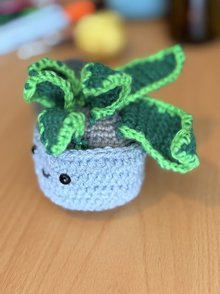 handmade crochet snake plant in a small pot with tall green leaves