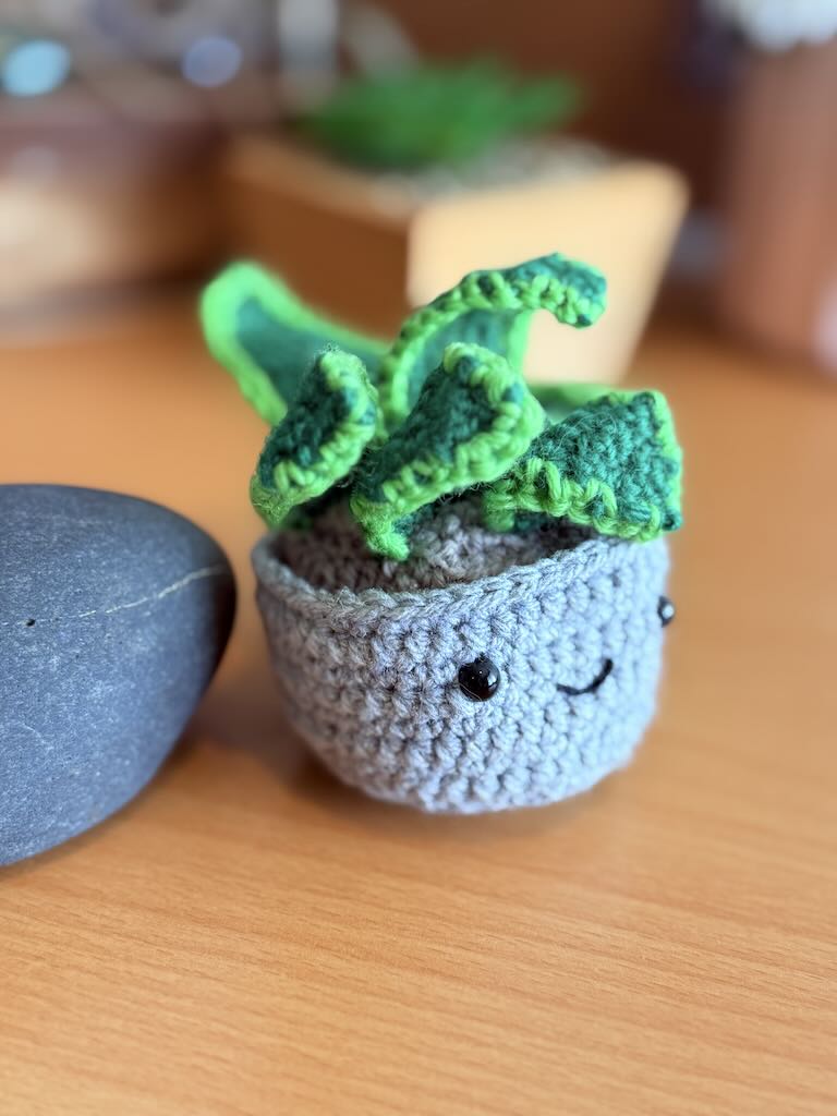 handmade crochet snake plant in a small pot with tall green leaves