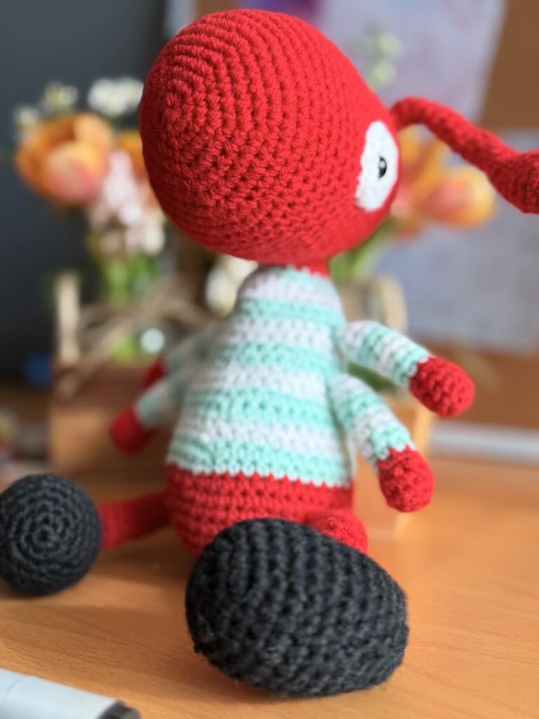 handmade crochet worker ant toy named Antony with tiny legs and stripey jumper