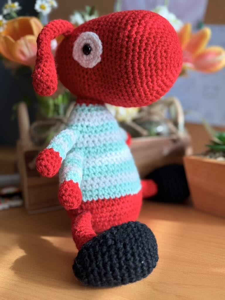 handmade crochet worker ant toy named Antony with tiny legs and stripey jumper